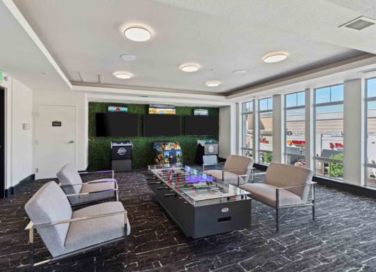 a lounge area with a table and chairs in a room with televisions