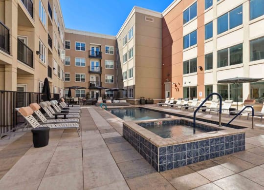 a jacuzzi pool and lounge chairs in an apartment building