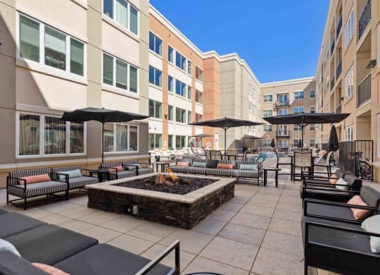 a patio with chairs and umbrellas and a fire pit