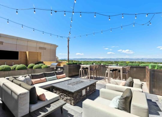 a rooftop patio with couches and chairs and a fire pit