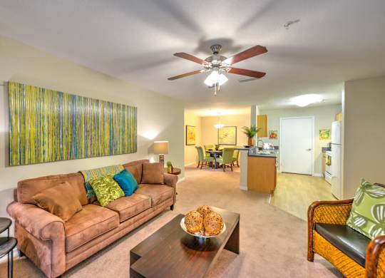 A living room with a brown couch and a ceiling fan.