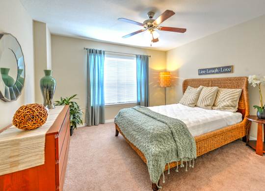 A bedroom with a bed, a ceiling fan, and a mirror on the wall.