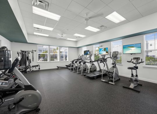 a gym with various exercise machines and windows