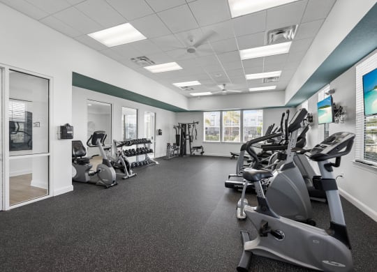 a gym with various exercise machines and a tv