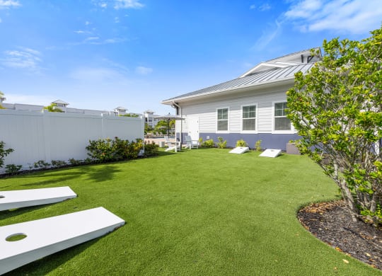 lawn area with corn hole game and a white fence