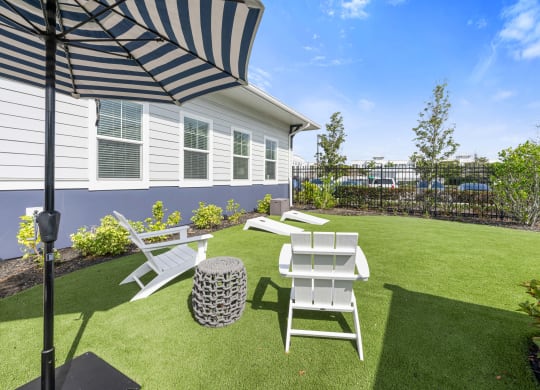 communal lawn area with a patio with chairs and an umbrella