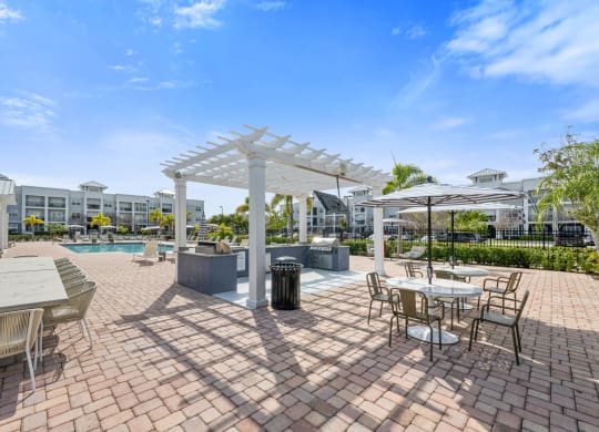 an outdoor patio with tables, grills and chairs and a swimming pool