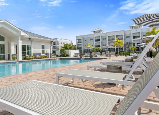 a swimming pool with lounge chairs and buildings in the background