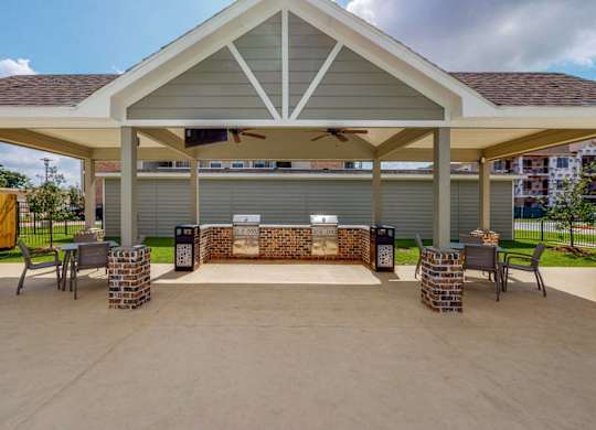 A covered patio area with a brick fireplace and seating area.