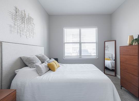 A bedroom with a bed, dresser, and mirror.
