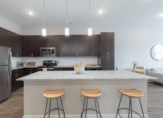 A modern kitchen with a granite countertop and bar stools.