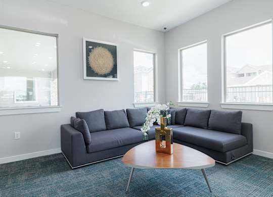 A grey couch sits in a room with a round table in front of it.