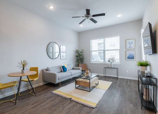 A living room with a yellow chair and a grey couch.