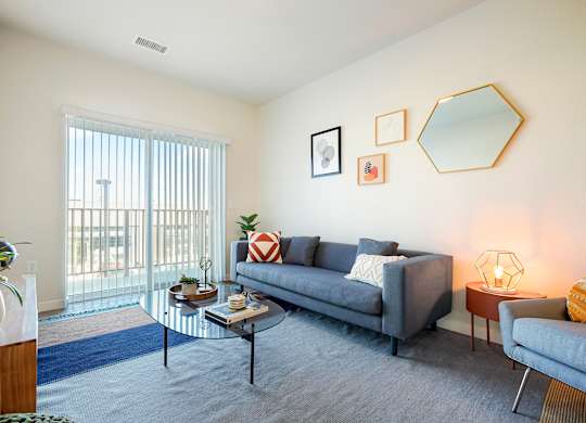 A living room with a grey couch, a coffee table, and a lamp.
