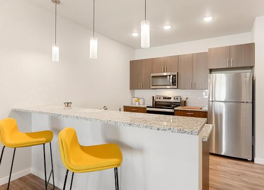 A kitchen with a white countertop and yellow chairs.
