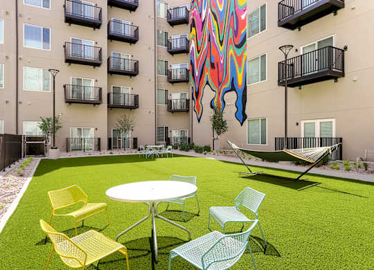 A patio with a table and chairs in front of a building.