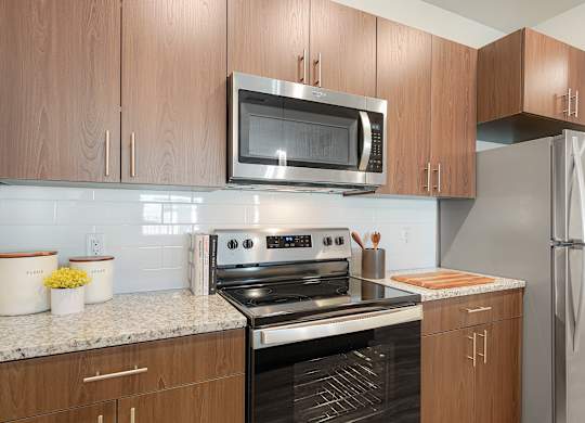 A kitchen with a stove, microwave, and refrigerator.