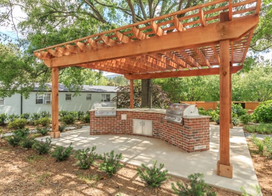 a backyard with a brick barbecue and a wooden pergola