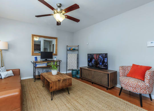 a living room with a ceiling fan and a tv
