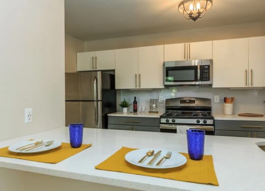 a kitchen with white cabinets and a white counter top with yellow place mats and purple vases
