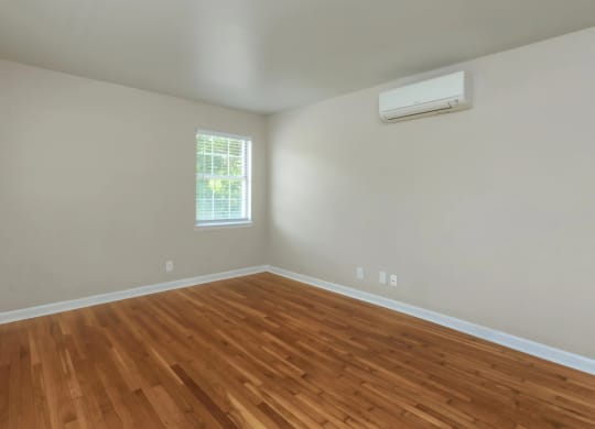 an empty room with a window and wooden floors