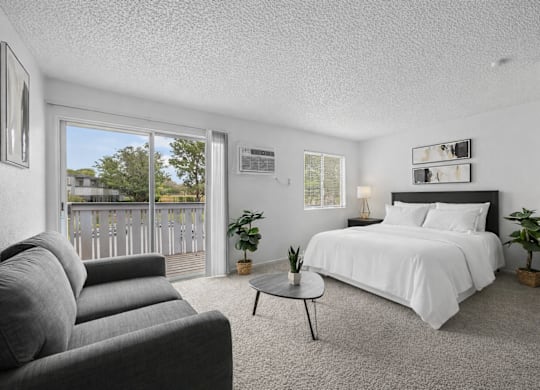 A bedroom with a large bed and a grey couch.
