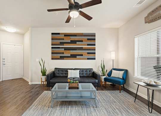 A living room with a black couch and a wooden wall hanging.