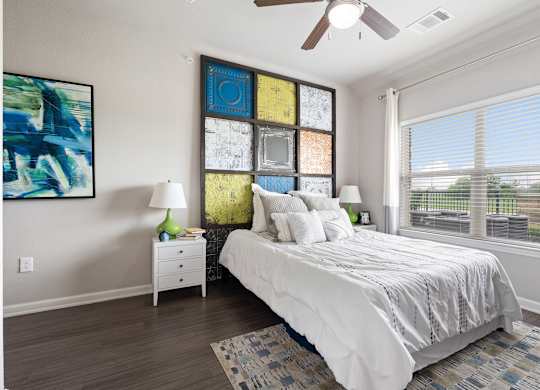 A bedroom with a bed, nightstand, and a painting on the wall.