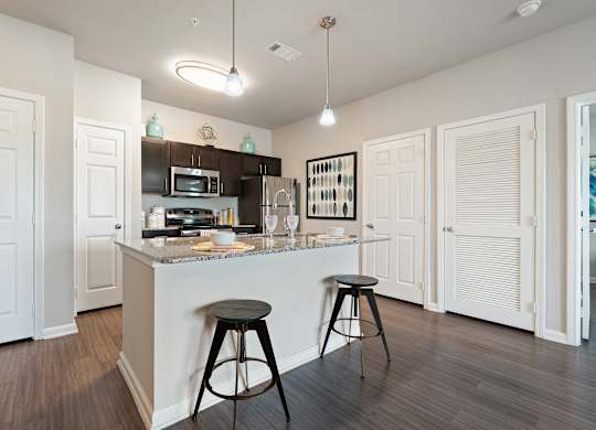 A kitchen with a bar stool in front of the counter.