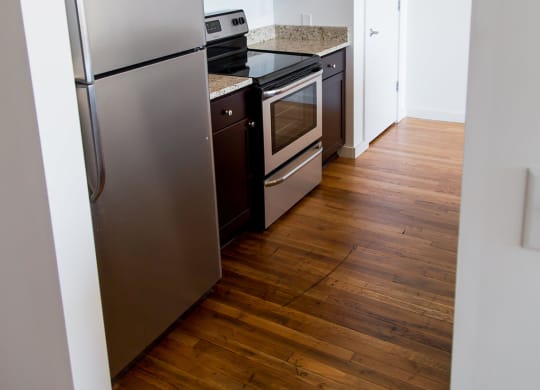 a small kitchen with stainless steel appliances and a wooden floor