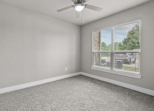 an empty room with a window and a ceiling fan