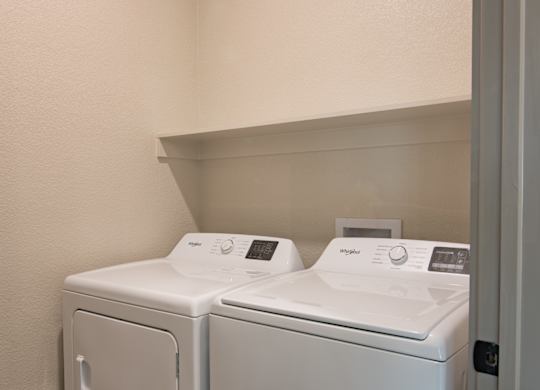Two white washing machines in a small laundry room.