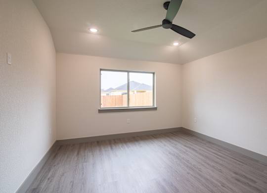 Empty room with a window and a ceiling fan.
