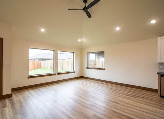 A room with a ceiling fan and two windows.