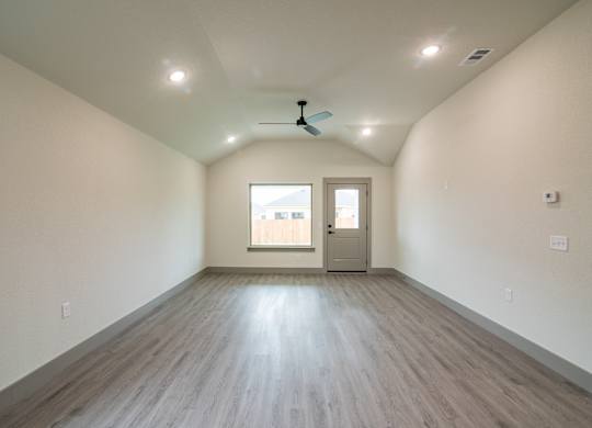 A room with a ceiling fan and a door leading to a balcony.