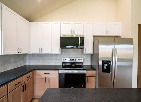 A kitchen with black countertops and stainless steel appliances.