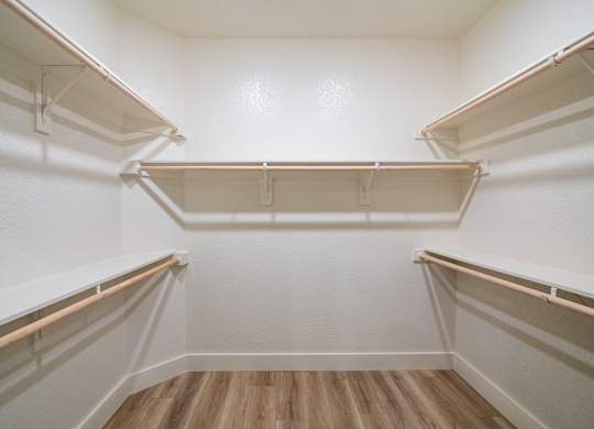 Empty white refrigerator with wooden floor and white walls.