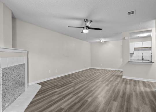 an empty living room with a ceiling fan and a fireplace