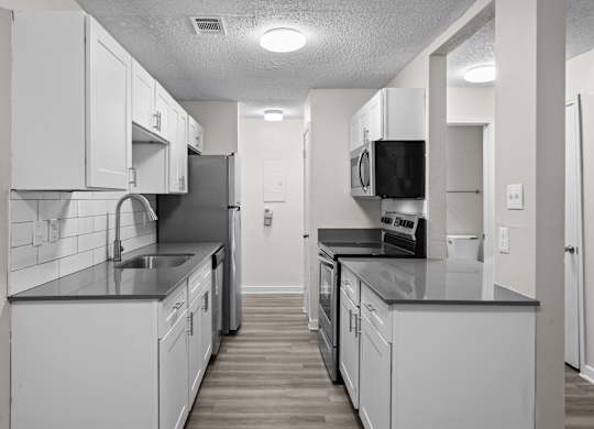 an empty kitchen with white cabinets and black counter tops