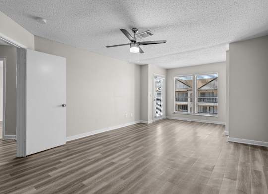 an empty living room with a ceiling fan and a window