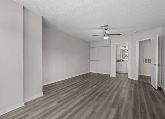 an empty living room with wood flooring and a ceiling fan