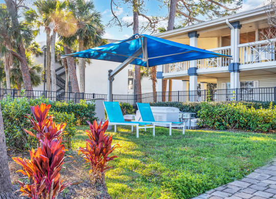 a patio with a blue umbrella and chairs in front of a building