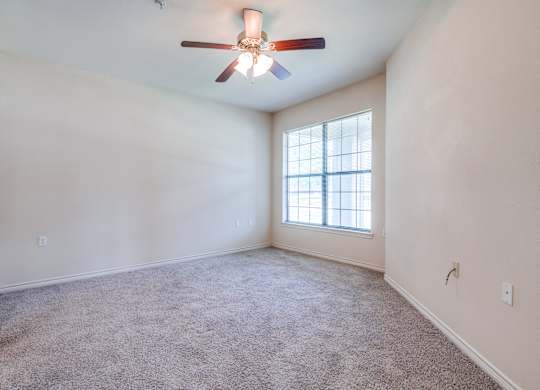 an empty living room with a ceiling fan and a window