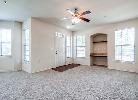 an empty living room with a ceiling fan