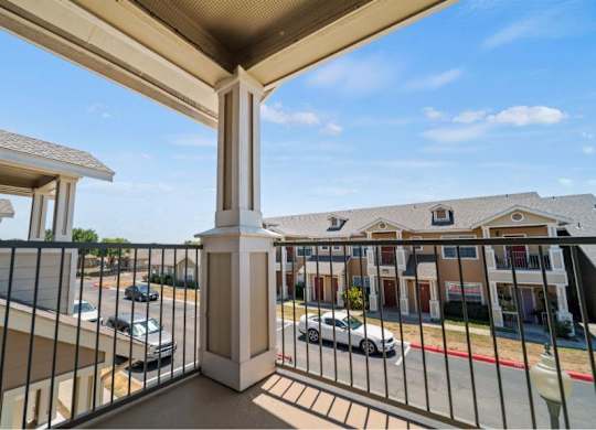 A balcony overlooks a parking lot and buildings.