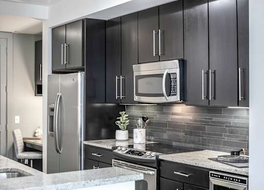 A modern kitchen with a stainless steel refrigerator and microwave.