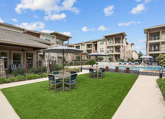 a backyard with tables and chairs and a pool with umbrellas