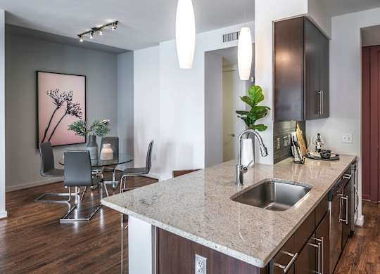 A kitchen with a marble countertop and wooden floors.