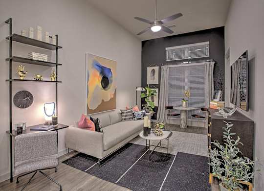 A living room with a white couch, a black shelf, and a painting on the wall.