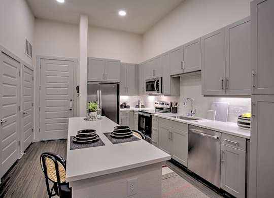 A kitchen with white cabinets and a white island with plates on it.